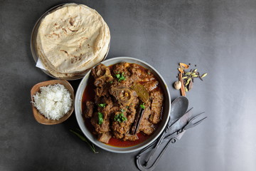 Overhead view of Goat curry, Mutton curry, Nihari, Rogan Josh in a bowl with Chapati and plain Rice.
