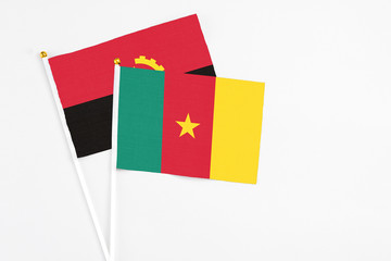 Naklejka premium Cameroon and Angola stick flags on white background. High quality fabric, miniature national flag. Peaceful global concept.White floor for copy space.
