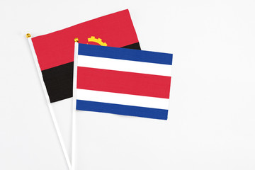 Costa Rica and Angola stick flags on white background. High quality fabric, miniature national...