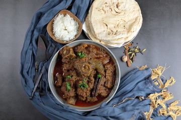 Overhead view of Goat curry, Mutton curry, Nihari, Rogan Josh in a bowl with Chapati and plain Rice.