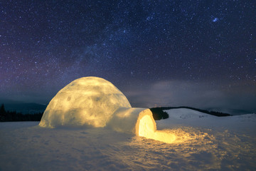 Fantastic winter landscape glowing by star light. Wintry scene with snowy igloo and milky way in...