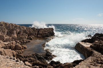 Waves crashing at stone shore. Saint Jean Cap Ferrat hiking trail, French Riviera, Cote d'Azur, France. 