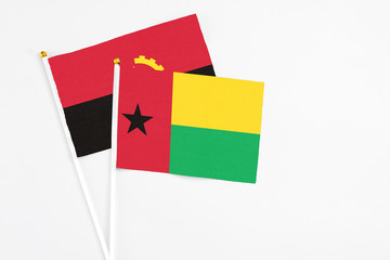Guinea Bissau and Angola stick flags on white background. High quality fabric, miniature national flag. Peaceful global concept.White floor for copy space.