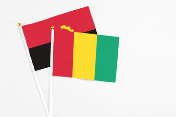 Guinea and Angola stick flags on white background. High quality fabric, miniature national flag. Peaceful global concept.White floor for copy space.