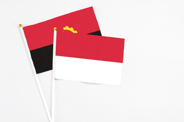 Indonesia and Angola stick flags on white background. High quality fabric, miniature national flag....
