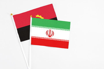 Iran and Angola stick flags on white background. High quality fabric, miniature national flag. Peaceful global concept.White floor for copy space.