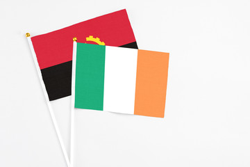 Ireland and Angola stick flags on white background. High quality fabric, miniature national flag....
