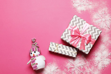 Gift boxes with a pink bow and a snowman on a pink background. place for text. Top view.