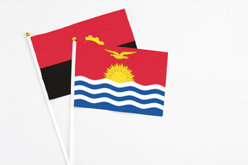 Naklejka premium Kiribati and Angola stick flags on white background. High quality fabric, miniature national flag. Peaceful global concept.White floor for copy space.