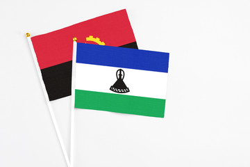 Lesotho and Angola stick flags on white background. High quality fabric, miniature national flag....