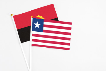 Liberia and Angola stick flags on white background. High quality fabric, miniature national flag. Peaceful global concept.White floor for copy space.