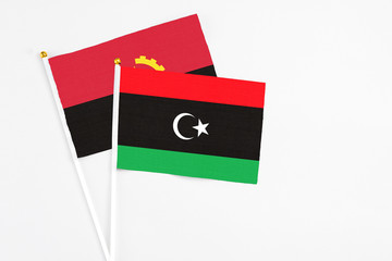 Libya and Angola stick flags on white background. High quality fabric, miniature national flag. Peaceful global concept.White floor for copy space.
