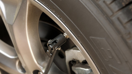 Closeup of air compressor inflation nozzle on valve stem of a car tire. Inflating automotive tire to proper air pressure.