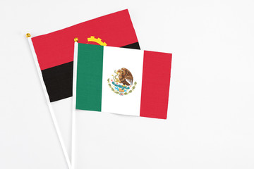 Mexico and Angola stick flags on white background. High quality fabric, miniature national flag. Peaceful global concept.White floor for copy space.