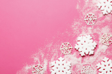 Snowflakes and snow decor on a pink background. place for text. Top view.