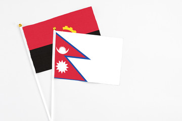 Nepal and Angola stick flags on white background. High quality fabric, miniature national flag....