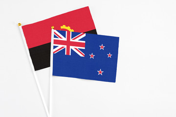 New Zealand and Angola stick flags on white background. High quality fabric, miniature national...