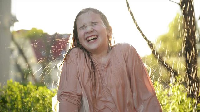 Young Happy Girl Having Fun Under Rain. Smiling Wet Kid Smile and Have Good Mood Outdoors.