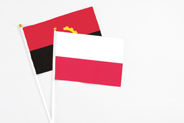 Poland and Angola stick flags on white background. High quality fabric, miniature national flag....