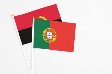 Portugal and Angola stick flags on white background. High quality fabric, miniature national flag. Peaceful global concept.White floor for copy space.