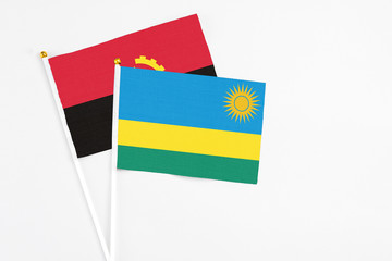 Rwanda and Angola stick flags on white background. High quality fabric, miniature national flag. Peaceful global concept.White floor for copy space.