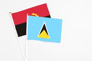 Saint Lucia and Angola stick flags on white background. High quality fabric, miniature national...