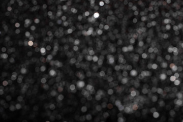 Monochrome abstract background with small bokeh defocused lights.