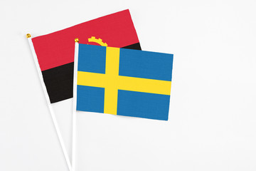 Sweden and Angola stick flags on white background. High quality fabric, miniature national flag. Peaceful global concept.White floor for copy space.