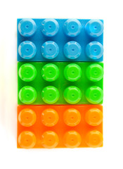  bricks of the children's designer of orange, blue and green on a white background. Flat lay