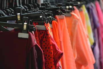 Fashionable brightly vivid colored clothes hanging on the rack in the fashion store
