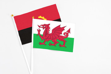 Wales and Angola stick flags on white background. High quality fabric, miniature national flag. Peaceful global concept.White floor for copy space.