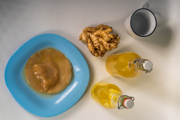 Mother Kombucha or SCOBY on a blue plate on a white background. Bottles of prepared kombucha and ginger.