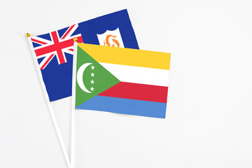 Comoros and Anguilla stick flags on white background. High quality fabric, miniature national flag. Peaceful global concept.White floor for copy space.