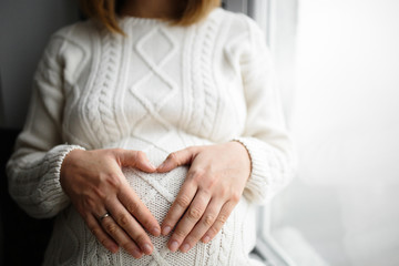 Hands in shape of heart on belly of pregnant woman