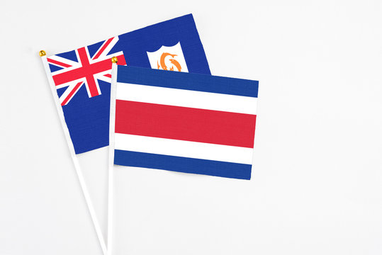 Costa Rica and Anguilla stick flags on white background. High quality fabric, miniature national flag. Peaceful global concept.White floor for copy space.
