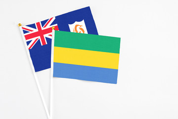 Gabon and Anguilla stick flags on white background. High quality fabric, miniature national flag. Peaceful global concept.White floor for copy space.