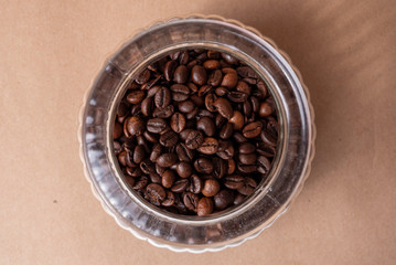 Freshly roasted coffee beans in a glass jar. On a stone background.