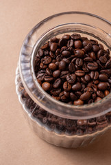 Freshly roasted coffee beans in a glass jar. On a stone background.