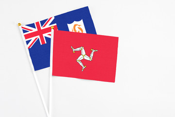 Fototapeta premium Isle Of Man and Anguilla stick flags on white background. High quality fabric, miniature national flag. Peaceful global concept.White floor for copy space.