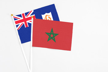 Morocco and Anguilla stick flags on white background. High quality fabric, miniature national flag. Peaceful global concept.White floor for copy space.