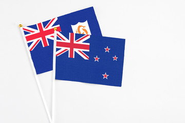 Fototapeta premium New Zealand and Anguilla stick flags on white background. High quality fabric, miniature national flag. Peaceful global concept.White floor for copy space.
