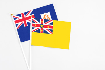 Fototapeta premium Niue and Anguilla stick flags on white background. High quality fabric, miniature national flag. Peaceful global concept.White floor for copy space.