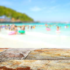 Brown stone table top with blurred people at the beach