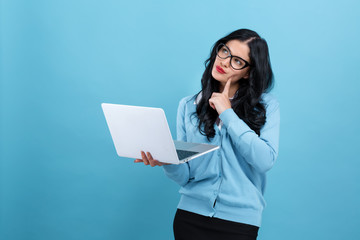 Young woman with a laptop computer in a thoughtful pose on a blue background