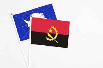 Angola and Antarctica stick flags on white background. High quality fabric, miniature national flag. Peaceful global concept.White floor for copy space.