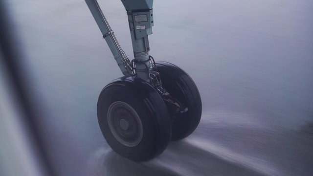 Airplane landing gear taxiing the runway in heavy rain