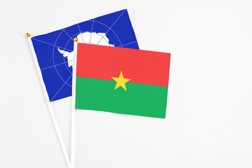Burkina Faso and Antarctica stick flags on white background. High quality fabric, miniature national flag. Peaceful global concept.White floor for copy space.