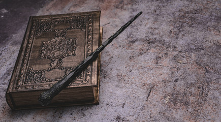 Old book with spells and magic wand on gray background. Copy space for text