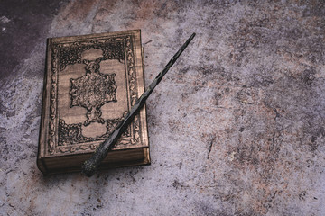 Old book with spells and magic wand on gray background. Copy space for text