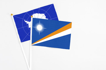 Marshall Islands and Antarctica stick flags on white background. High quality fabric, miniature national flag. Peaceful global concept.White floor for copy space.